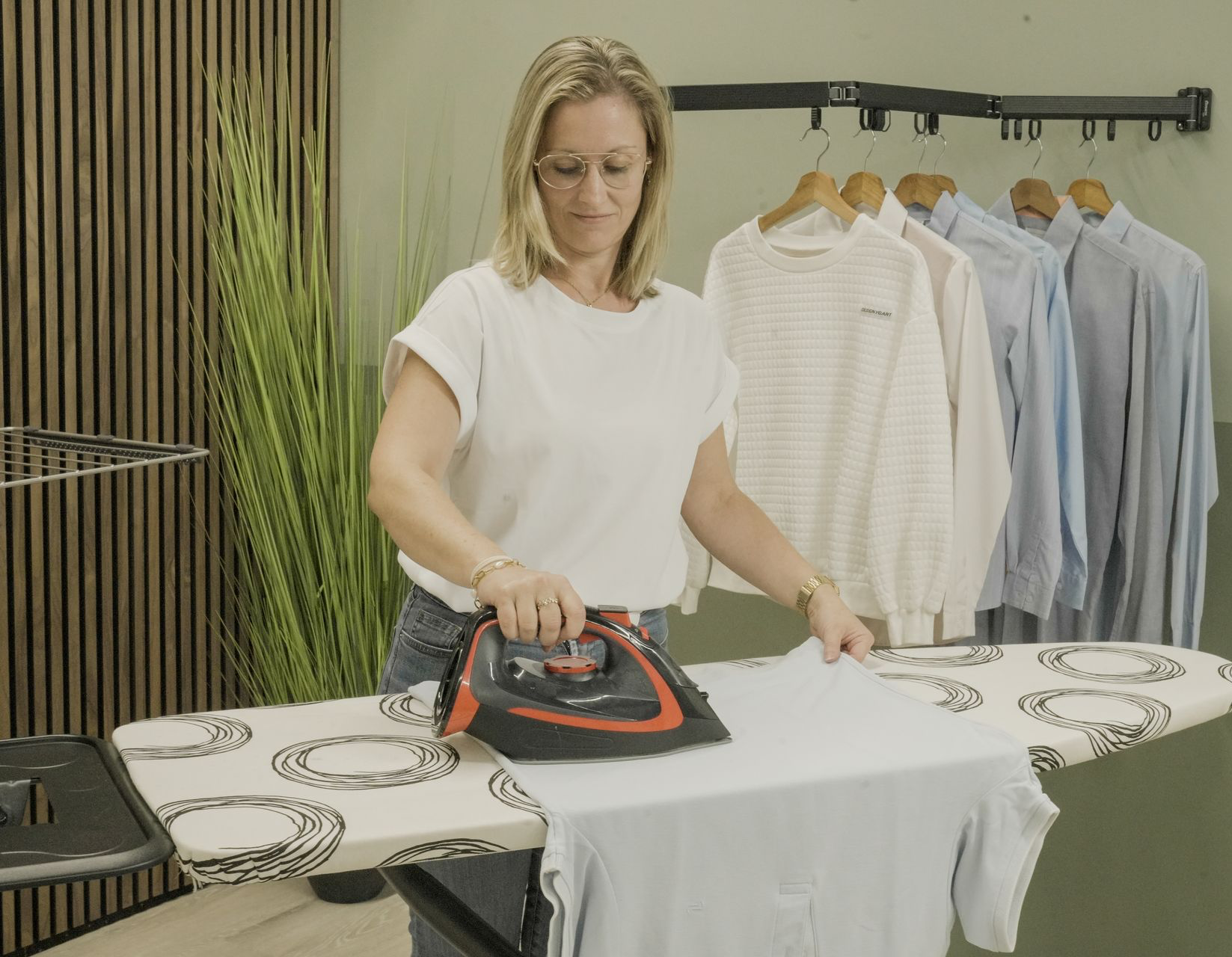 Stevige en veilige strijkplank met in de achtergrond in droogtoren en wanddroogrek op kledij aan op te hangen